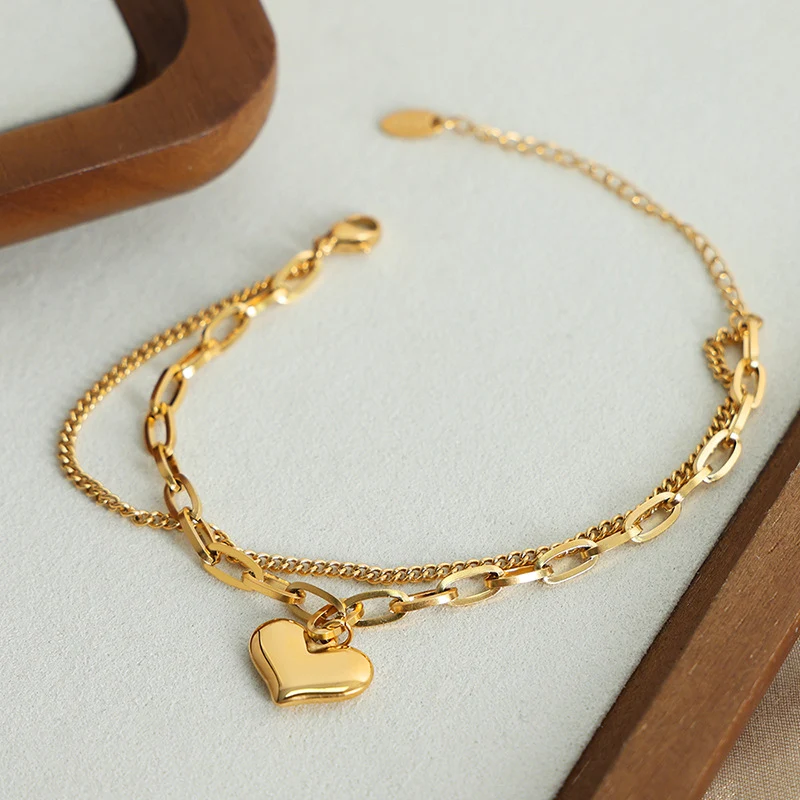 Pulseira com pingente de coração duplo em aço titânio banhado a ouro. Amor eterno, elegância duradoura e design moderno. — foto 4
