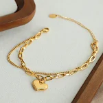 Pulseira com pingente de coração duplo em aço titânio banhado a ouro. Amor eterno, elegância duradoura e design moderno. — foto 4