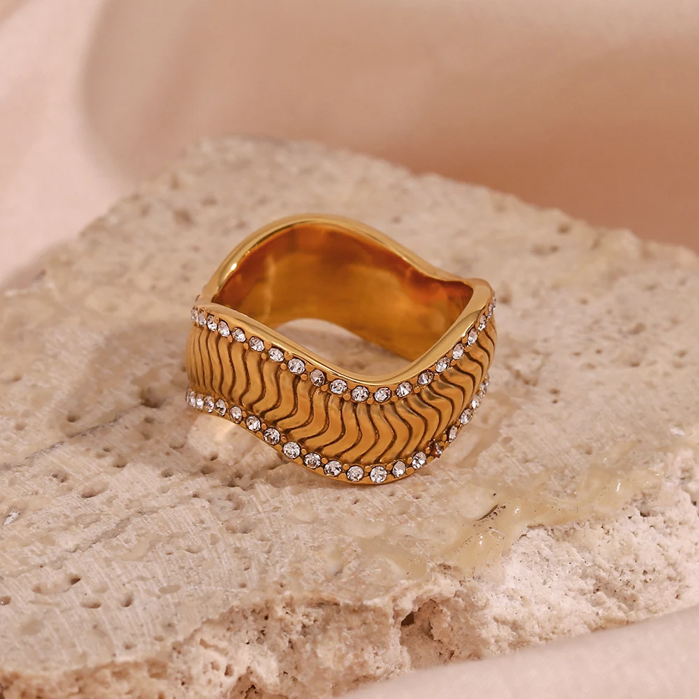 Anel de twill ondulado em aço inoxidável com banho de ouro 18k e pedras nas laterais. Elegância e brilho para o dia a dia. — foto 6
