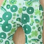 Calças infantis verdes de sino com estampa de trevo de quatro folhas e alças, um look charmoso e confortável para sua bebê menina. — foto 1