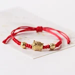 Pulseira de porquinho com corda trançada vermelha e liga ajustável. Um acessório charmoso e moderno para pulsos de todas as idades. — foto 11